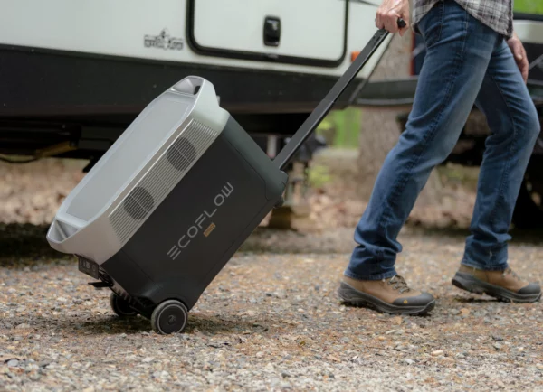 Générateur portable EcoFlow DELTA Pro 3600W en déplacement, tiré par une personne sur un terrain gravillonné, démontrant la mobilité de l'unité d'énergie avec ses roues et sa poignée télescopique