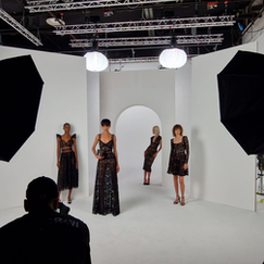 Vue d'une séance photo en studio montrant quatre femmes en robes de soirée noires, avec des lumières de studio et des équipements de photographie visibles